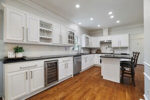 A spacious kitchen with white cabinetry, a central island, and a wooden floor. - La Belle Vie 
Hot Tub • Fire Pit • Outdoor Kitchen • Sleeps 12 (Lake Ariel)