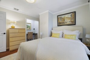 A hotel room with a bed, a dresser, a desk, and a painting on the wall. - La Belle Vie 
Hot Tub • Fire Pit • Outdoor Kitchen • Sleeps 12 (Lake Ariel)