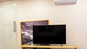 Ein modernes Wohnzimmer mit einem Flachbildfernseher auf einem Holzständer, einer Glastür mit Zeitanzeige und einem gemusterten Teppich auf dem Boden.