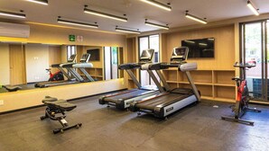 Ein Fitnessraum mit Laufbändern, einem Ergometer und einem Spiegel, der Trainingsgeräte reflektiert.