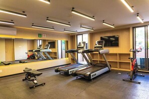 A gym with treadmills, a stationary bike, and a mirror reflecting exercise equipment. - Unwind in Guadalajara | Torre Villadhara (Guadalajara)