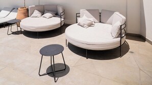 Zona lounge sul tetto con due spazi salotto circolari, un tavolino e una pianta in vaso.