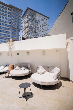 Eine Dachterrasse mit zwei Sitzbereichen, einem kleinen Tisch und einem Blumentopf.