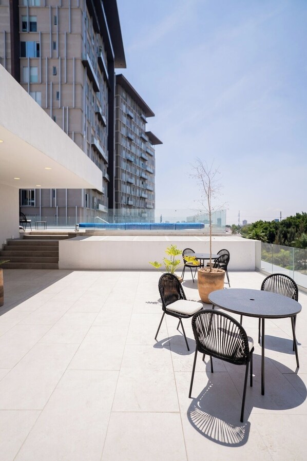 Eine Terrasse im Freien mit Tisch, Stühlen, einem Blumentopf und einer Treppe, die zu einer oberen Ebene führt.