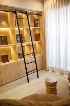 A modern interior with a wooden bookshelf, a ladder, and a window with curtains. - Mr. W | A Relaxing Stay Near Downtown GDL | Villadhara (Guadalajara)
