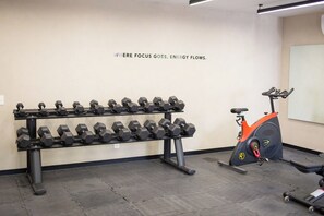 Ein Fitnessraum mit Hanteln an Gestellen und einem Ergometer.