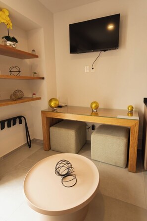 Ein modernes Wohnzimmer mit einem an der Wand befestigten Flachbildfernseher, einem Holztisch und einer Bank mit Kissen.