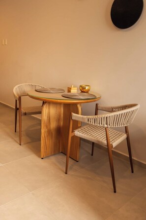 A round wooden table with two chairs, a gold bowl, and a woven basket on it. - Mr. W | A Relaxing Stay Near Downtown GDL | Villadhara (Guadalajara)
