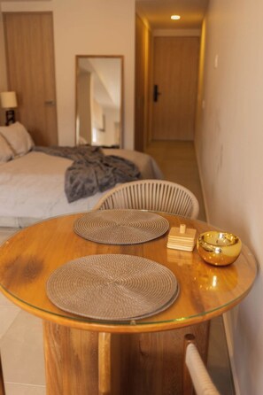 A hotel room with a bed, a round wooden table with placemats, a bowl, and a chair. - Mr. W | A Relaxing Stay Near Downtown GDL | Villadhara (Guadalajara)