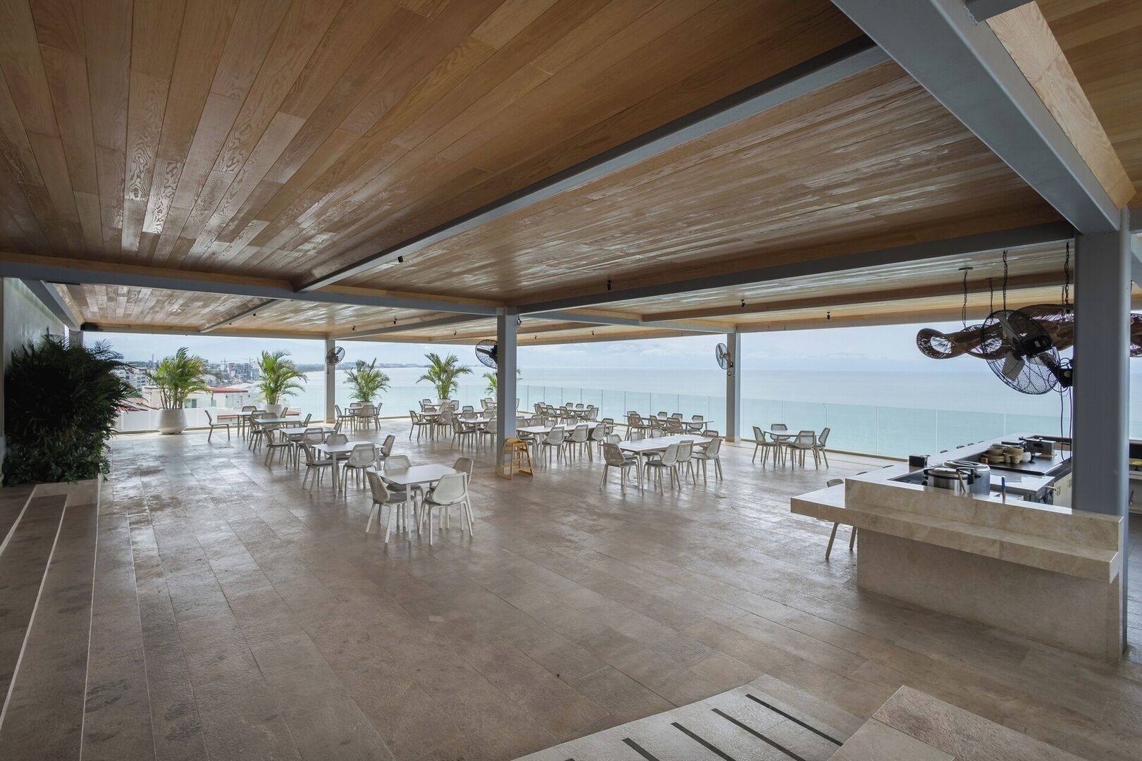 Un espace de restauration en plein air avec des tables et des chaises, un comptoir et une vue sur la mer.
