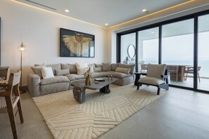 A modern living room with a sectional sofa, a coffee table, and a view of the outdoors through large windows. - Mr. W | Stunning 3-Bedroom Apartment in Bantay | Bucerías (Bucerías)