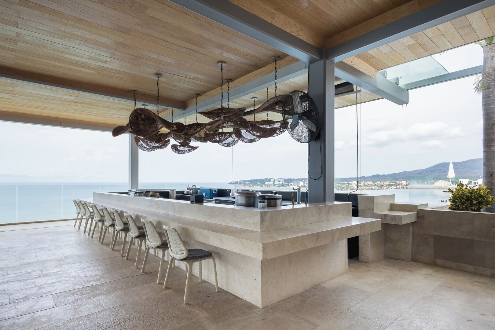 Un bar moderne doté d’un long comptoir et de nombreuses chaises, offrant une vue panoramique sur la côte.