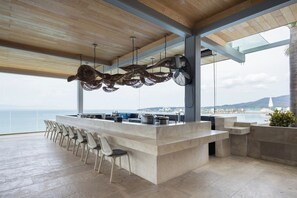 A modern bar area with a long counter and multiple chairs, overlooking a scenic coastal view. - Mr. W | Stunning 3-Bedroom Apartment in Bantay | Bucerías (Bucerías)