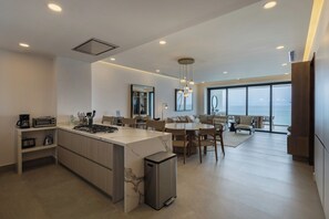 A modern kitchen with a central island, dining area with chairs, and a large window offering a view. - Mr. W | Stunning 3-Bedroom Apartment in Bantay | Bucerías (Bucerías)