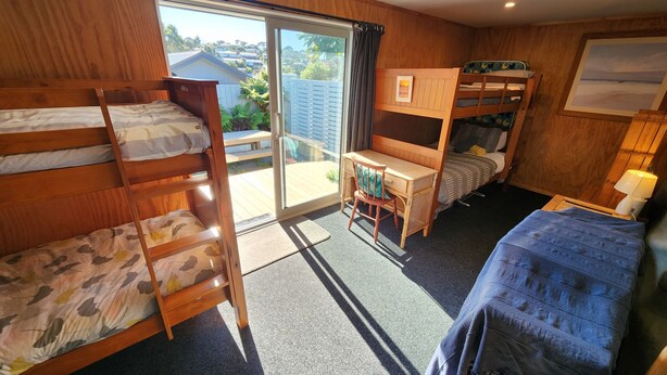 Een kleine kamer met stapelbedden, een bureau en een stoel.