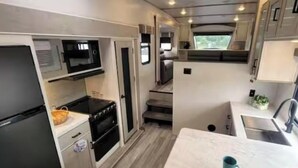 A compact kitchen with a microwave, oven, and sink. - Peaceful 1-bedroom recreational vehicle with AC in Cleveland (Cleveland)