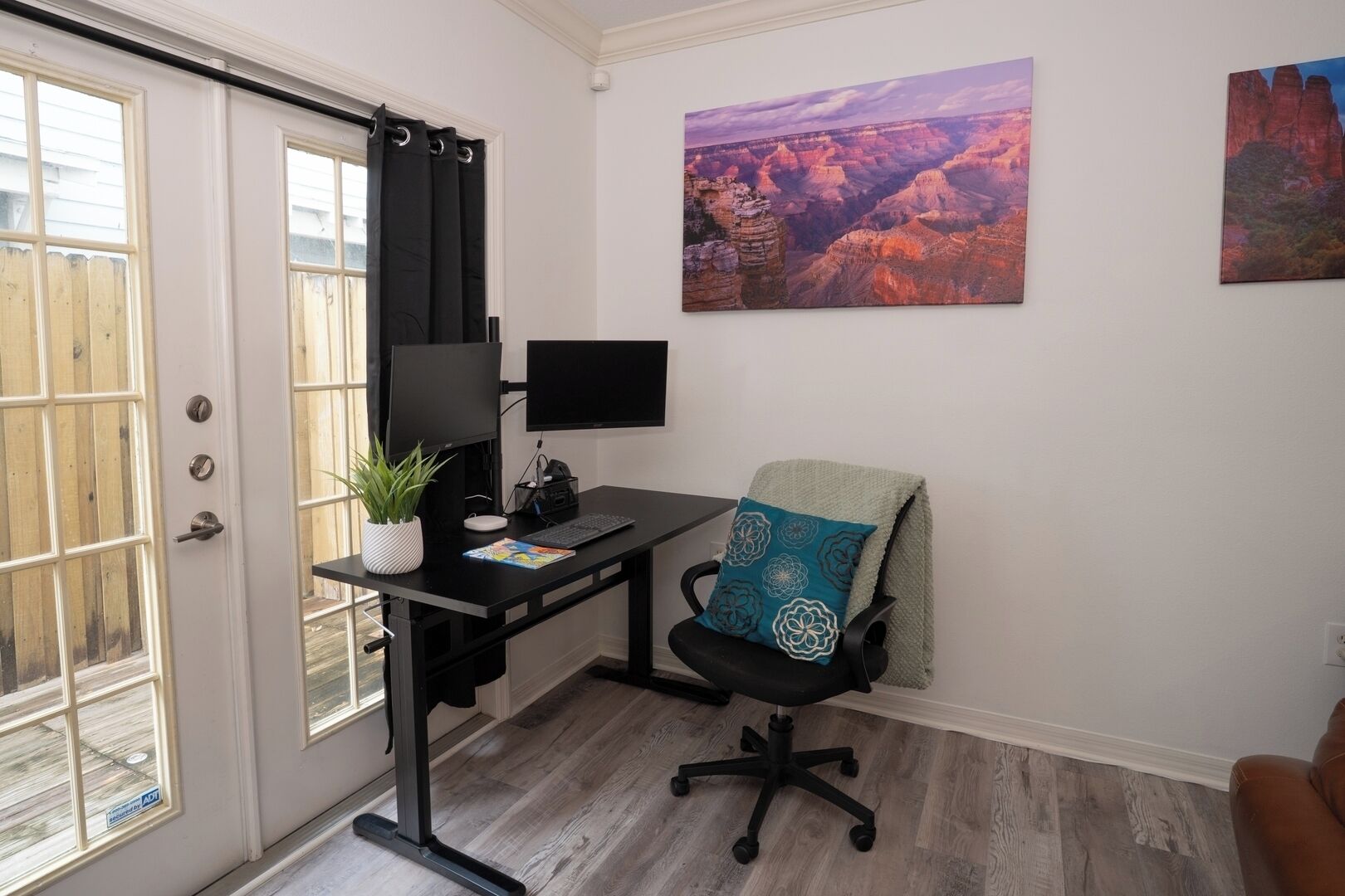 A home office with a desk, computer, chair, and a window with curtains.