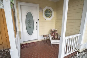 Eine Veranda mit einer weißen Tür, einem kleinen Tisch und einem Stuhl mit Blumenmuster.