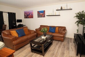 A living room with two brown leather sofas, a glass coffee table, and a TV on a stand. - Prime Location • Gym • Dual-Monitor Workspace (Tampa)