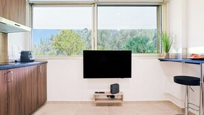A modern kitchen with a large window, a flat-screen TV, and a coffee machine. - Upstays Cosy Studio 15m² with pool and quiet (Cannes)