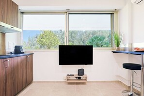 A modern kitchen with a large window, a flat-screen TV, and a coffee machine. - Upstays Cosy Studio 15m² with pool and quiet (Cannes)