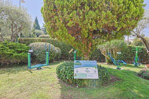 A park with exercise equipment, a sign, and well-maintained greenery. - Upstays Cosy Studio 15m² with pool and quiet (Cannes)