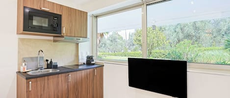 A modern kitchen with a built-in microwave, a sink, and a window with a view of greenery.