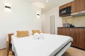 Una habitación de hotel con una cama, un armario de madera, un microondas y un lavabo.