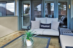 A covered patio area with a sofa, cushions, and a potted plant. - 2BR/2.5BA Bear Meadows Condo on Golf Course (Big Bear Lake)