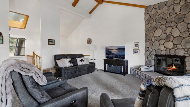 Ein gemütliches Wohnzimmer mit Kamin aus Stein, einer bequemen Couch und einem Fernseher.
