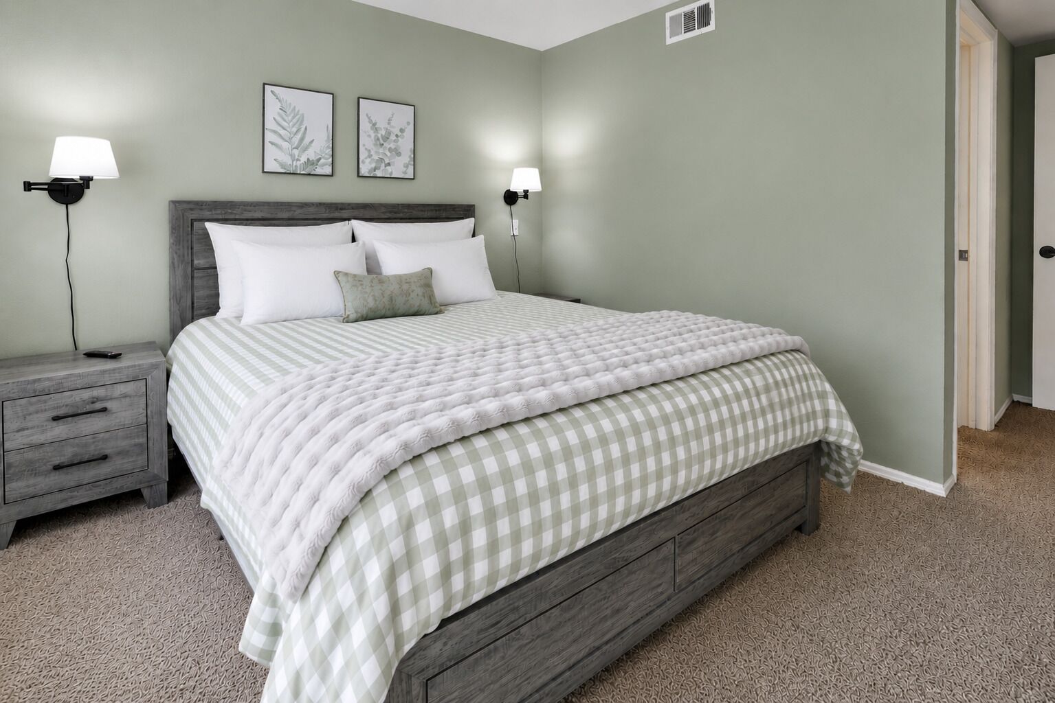 A bedroom with a bed, nightstands, wall-mounted lamps, and framed botanical prints.