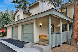 A two-story building with a covered porch, two garage doors, and a bench. - 2BR/2.5BA Bear Meadows Condo on Golf Course (Big Bear Lake)