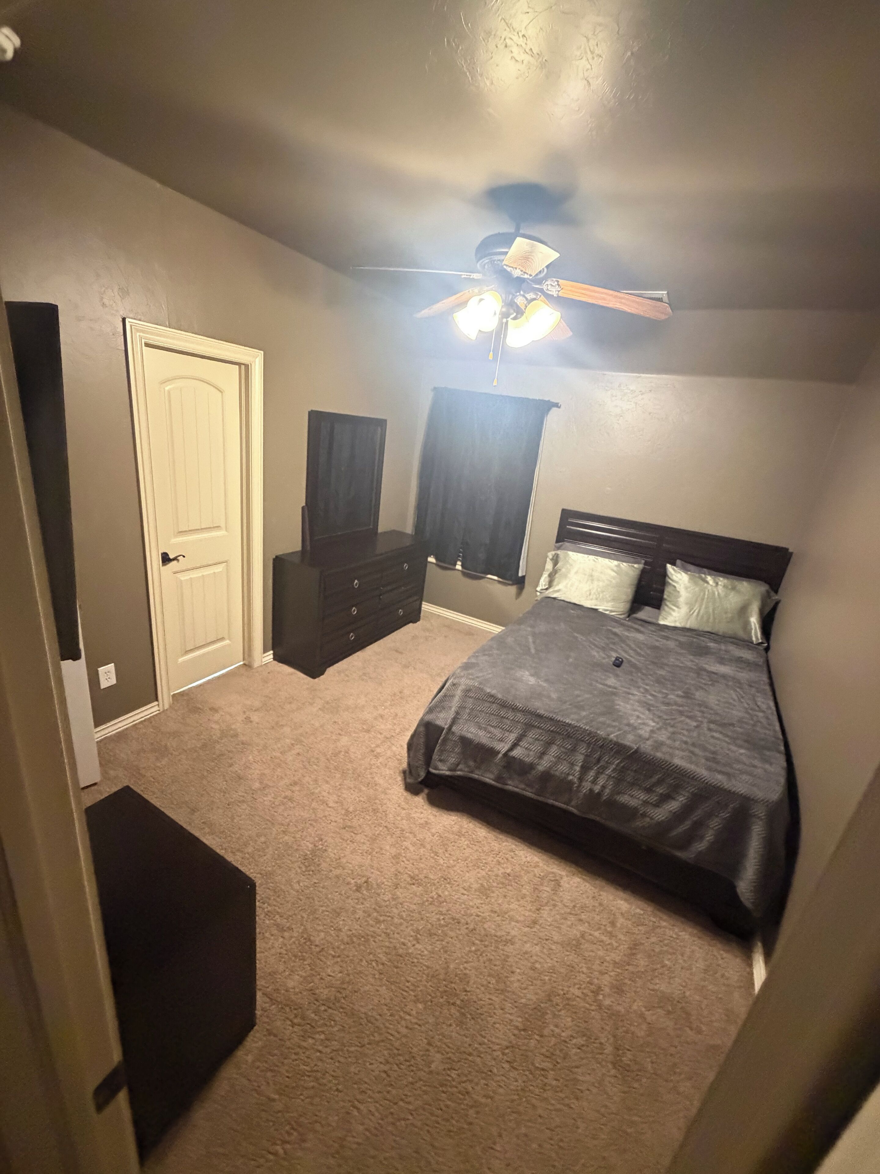 Ein Schlafzimmer mit Bett, Schminktisch und Deckenventilator.