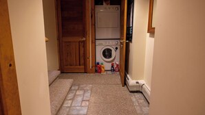 A laundry room with a washing machine, dryer, and a door leading to another room. - Mountains, golfing, hiking, tram and waterpark! (Jay)