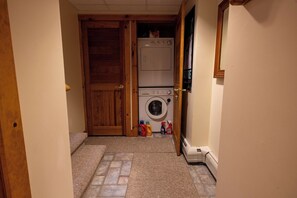 A laundry room with a washing machine, dryer, and a door leading to another room. - Mountains, golfing, hiking, tram and waterpark! (Jay)