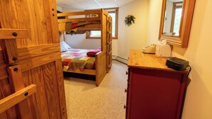 A bunk bed with a quilt, a wooden desk with a telephone, and a mirror on the wall. - Mountains, golfing, hiking, tram and waterpark! (Jay)