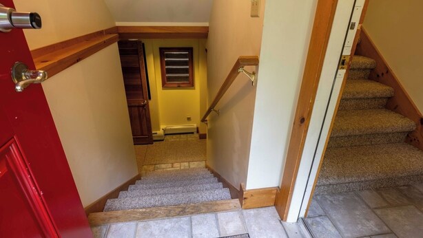 A staircase leading to a second floor with a red door on the left and carpeted stairs. - Mountains, golfing, hiking, tram and waterpark! (Jay)