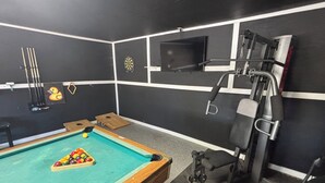 A billiards table with balls and cues, a dartboard, and a television screen mounted on the wall. -    Cozy Three bedroom, Family-Friendly Home with Pool, Game Room & Fast Wi-Fi (Corpus Christi)