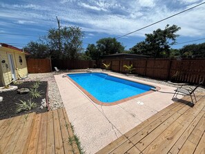 Une piscine rectangulaire entourée d’une terrasse en bois.