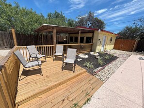 Eine Holzterrasse mit Sitzgelegenheiten und einem überdachten Bereich.