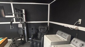 A laundry room with a washing machine, dryer, and a massage chair. -    Cozy Three bedroom, Family-Friendly Home with Pool, Game Room & Fast Wi-Fi (Corpus Christi)