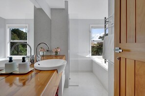 A modern bathroom with a wooden vanity, a large sink, and a glass shower enclosure. - Views on Devon West - New Plymouth (New Plymouth)