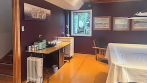 A room with a wooden ceiling, a desk with a kettle, a radiator, and a window with a view of greenery. - Views on Devon West - New Plymouth (New Plymouth)
