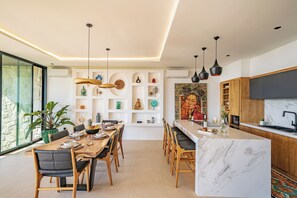 Une cuisine moderne avec un plan de travail en marbre, des armoires en bois et des luminaires suspendus.