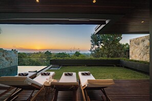 Une terrasse sur le toit, avec des chaises longues et une vue sur le coucher de soleil.