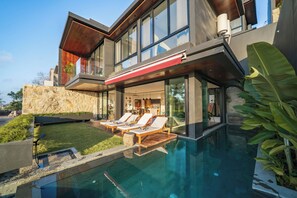 A modern house with a swimming pool, outdoor seating, and a stone wall. - Villa Sukha Senja Bingin (Pecatu)
