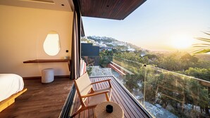 Ein Schlafzimmer mit großem Fenster, einem Bett, einem Nachttisch und einem Sessel.