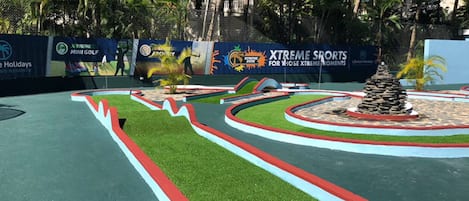 Un parcours de mini-golf avec un chemin sinueux, une petite colline et une structure en pierre.