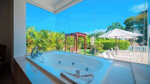 A bathroom with a large bathtub and a view of a garden with a gazebo and umbrellas. - VIP Villa at All-Inclusive Resort 3B (Confresi Beach)