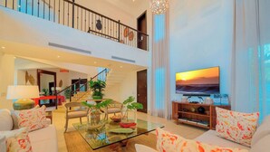A spacious living room with a glass coffee table, comfortable seating, a television, and a staircase leading to an upper level. - VIP Villa at All-Inclusive Resort 3B (Confresi Beach)